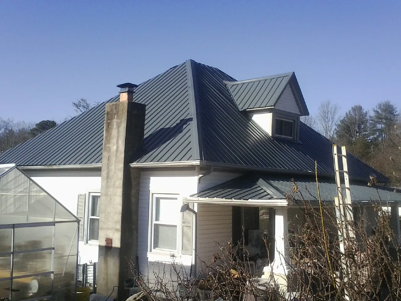Dark blue standing seam metal roof on a white farmhouse with dormer — Slate & Tile Roof Repair by Roofing Brothers in Nelson