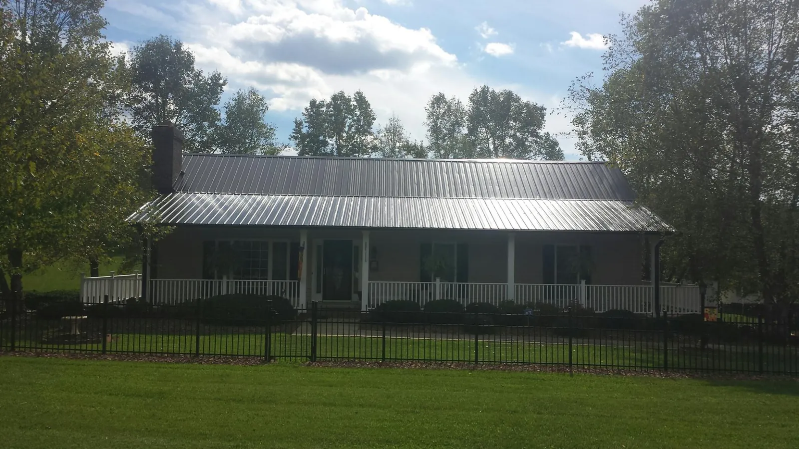 Gray metal roof on a brick ranch with a full width front porch — Gutter Guard Installation work by our crew in Nelson